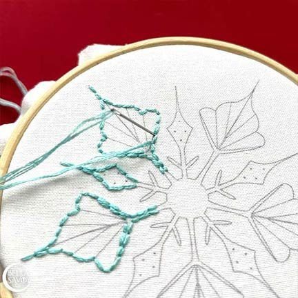 back stitch being added the the outer points of a snowflake embroidery design