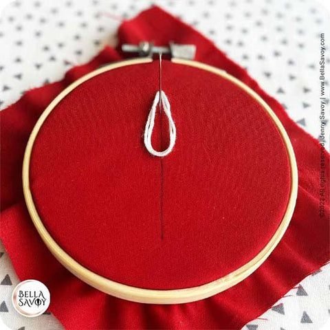 loop at the top of fabric with needle coming up through it.