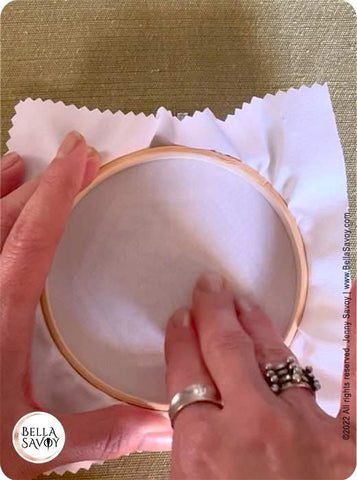 rubbing the back of fabric on an embroidery hoop