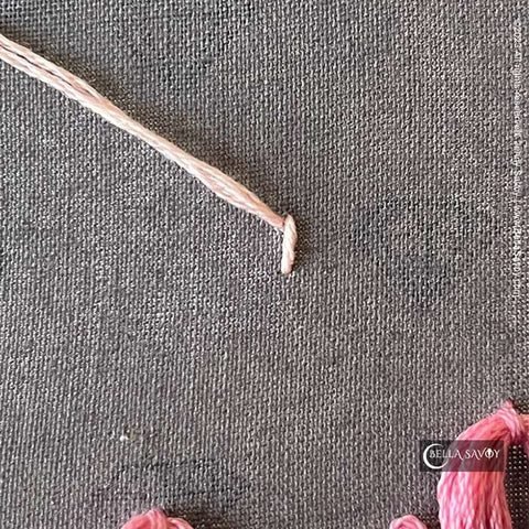 single stitch with thread coming up at the top left